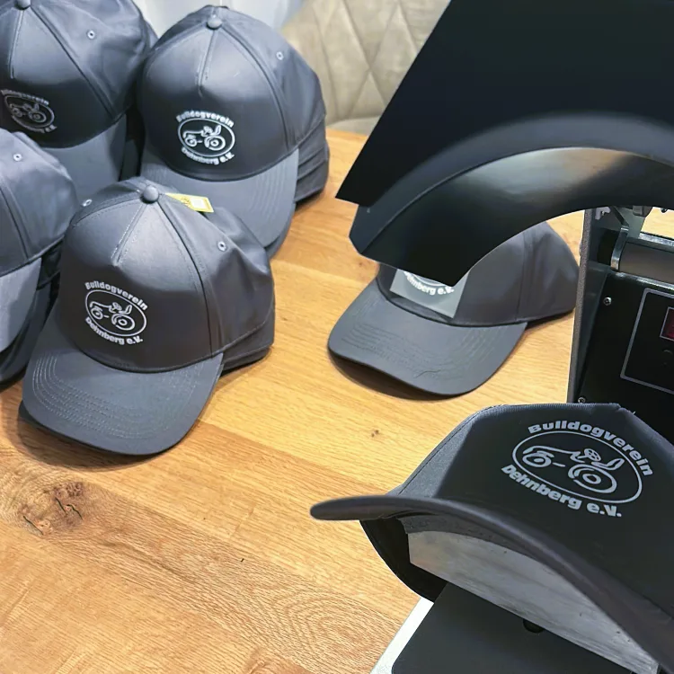 Mehrere graue Caps mit gesticktem Vereinslogo